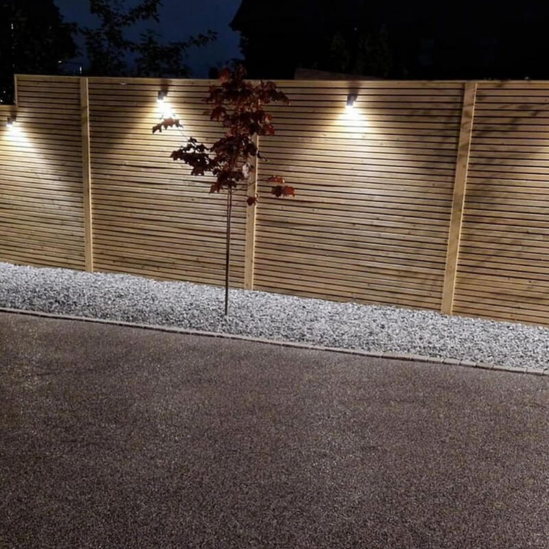 Lighting has been used to enhance the slatted fence panels at night.