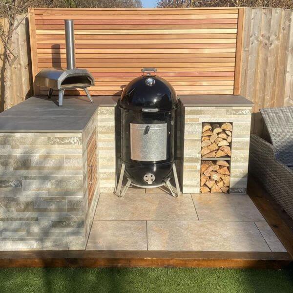This outdoor kitchen area uses Canadian cedar, beige cladding and anthracite paving to create a modern haven.